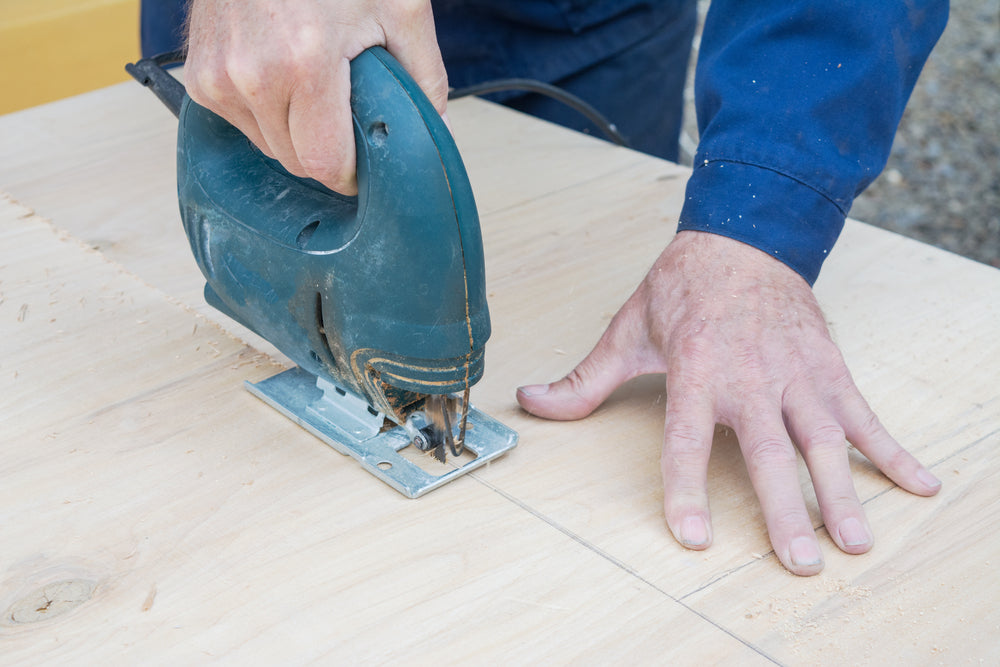 plywood sheet cut with an electric saw.man cuts sheet material.